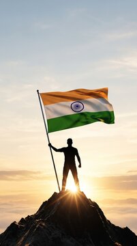 A silhouette standing on a mountain peak holding a waving national flag against a golden sunrise for Independence Day leadership success