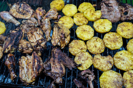 Parrillada mixta con pollo, carne de res y patacones asados sobre brasas en una parrilla