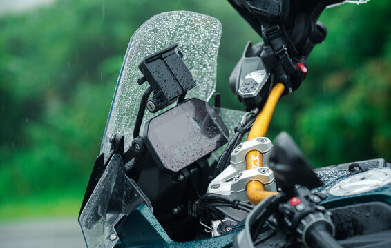 Motorcycle handlebar with GPS mount and raindrops on windshield, showcasing adventure and exploration