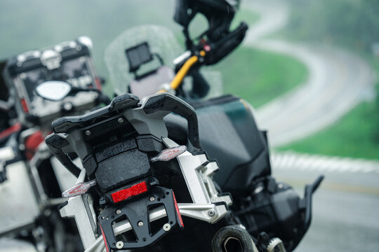 Adventure motorcycles parked on rainy mountain road, showcasing rugged design and wet conditions