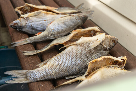 Homemade salted and dried fish prepared after recreational fishing on rustic wooden table
