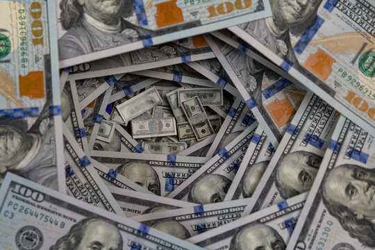 Miniature stacks of money inside a swirling tunnel of US one hundred dollar bills