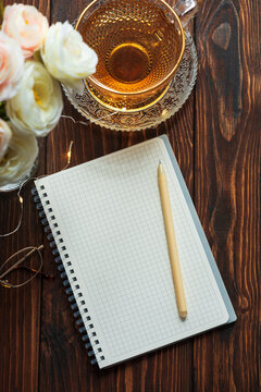 Morning routine with notebook, tea and flowers on wooden table