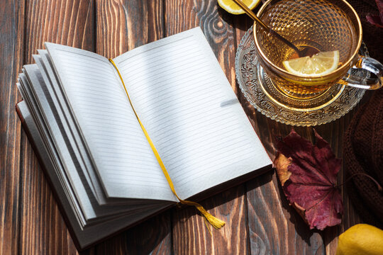 Opening notebook with lemon tea and autumn leaves