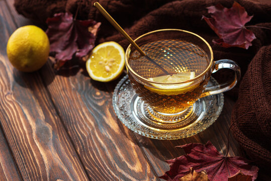 Hot tea with lemon and autumn leaves on wooden table