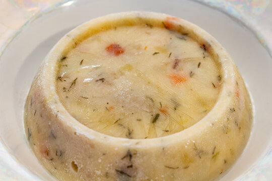Traditional meat aspic jelly with vegetables and herbs served in a white bowl