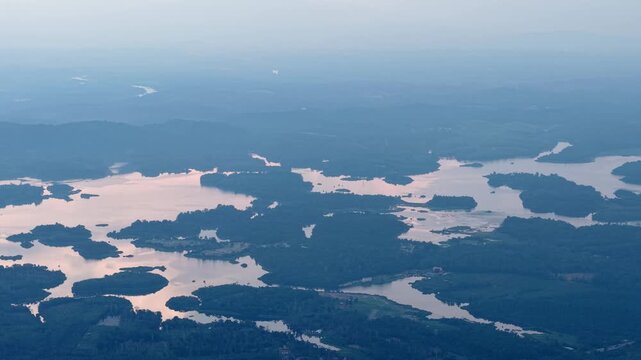 A tranquil aerial landscape showing a sprawling lake with scattered islands and dense forest under a soft dusk sky at Tasik Raban