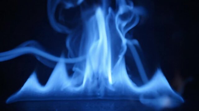 Abstract close up of intense blue gas flame burning steadily against a dark black background