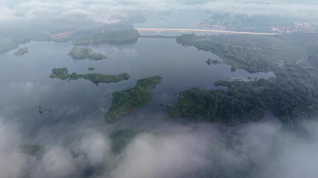 Aerial drone captures vast lake and islands. Misty clouds surround the water surface at Tasik Raban