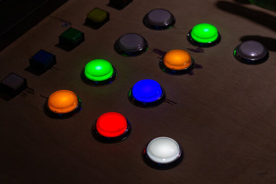 Colorful glowing push buttons on a control panel in dark room