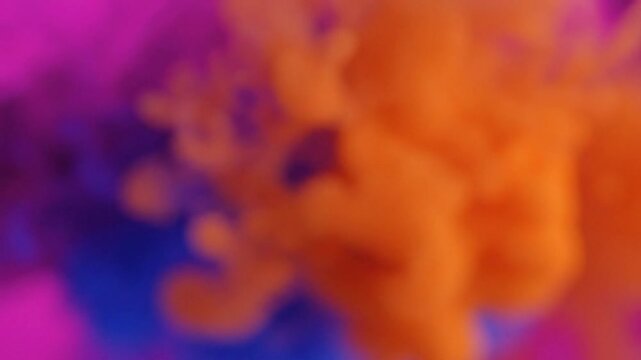 Vibrant abstract background of orange blue and purple ink clouds swirling together in slow motion