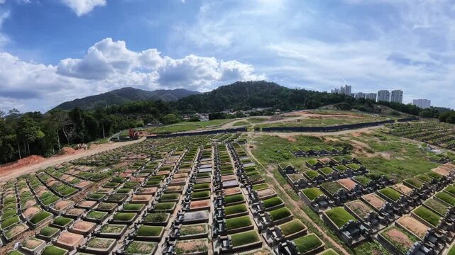 Vast cemetery stretches under bright blue sky. Rows of Chinese graves align neatly in geometric patterns at Mount Erskine, Penang