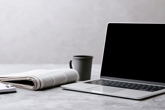 Open Laptop With Folded Newspaper in Workspace