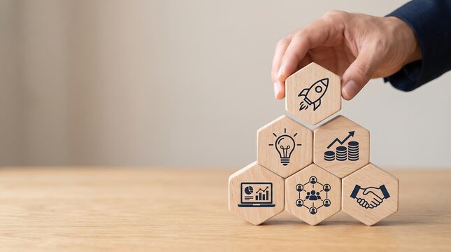 A hand placing a rocket icon block on a pyramid of business strategy and growth concepts, symbolizing innovation and success.