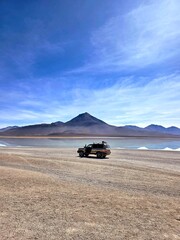 Off‑road vehicle parked in a remote desert landscape near a reflective lake © SolangelEstefania