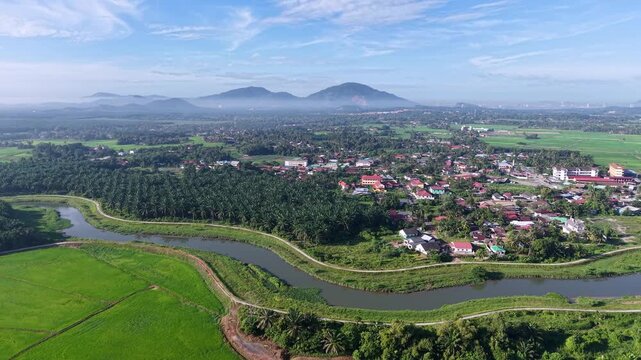 Aerial view captures a meandering river through lush green fields at Kubang Semang