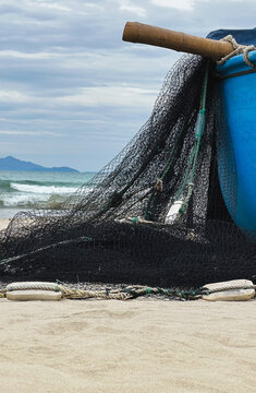 Fishing net drying on sandy beach with ocean waves and cloudy sky