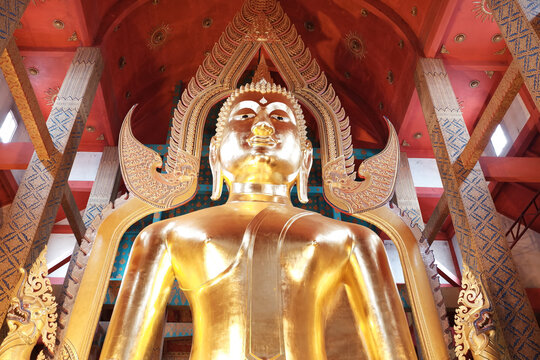 Low angle view of giant golden Buddha statue inside Thai temple main hall.