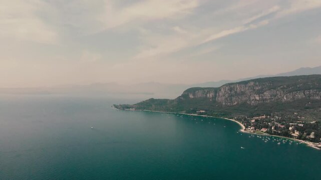 Horizontal 4K 30fps drone video flying over the cliffs of Rocca di Garda, revealing the scenic blue bay and town coastline in Lake Garda, Italy