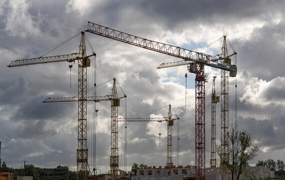 Construction site with tower cranes under dramatic cloudy sky