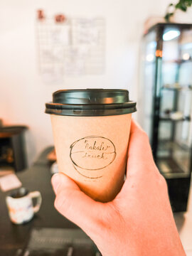 Prague, Czech republic - June 7, 2026: Hand holding take away coffee cup in cafe satalice