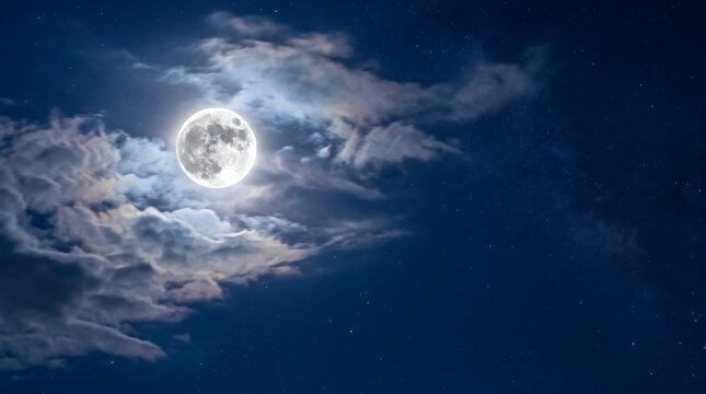 Full moon emerging from dramatic clouds at night with starry sky