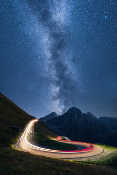 Light Trails and Milky Way Over Alpine Pass Road at Night
