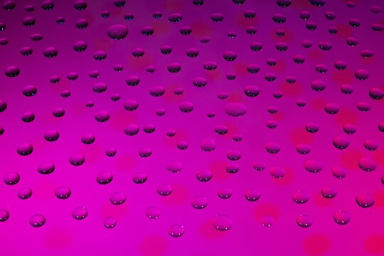 Close-up of pink glitter particles scattered on dark background. Sparkling cosmetic texture for beauty and fashion design projects.