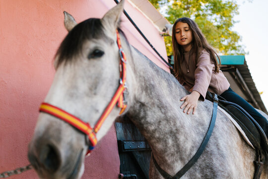 Young girl bonding with horse during riding lesson