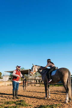 Coach teaching female rider horsemanship skills