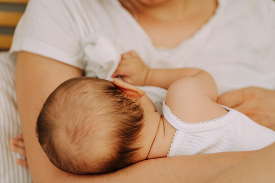 Close-up of mother holding newborn baby to her chest