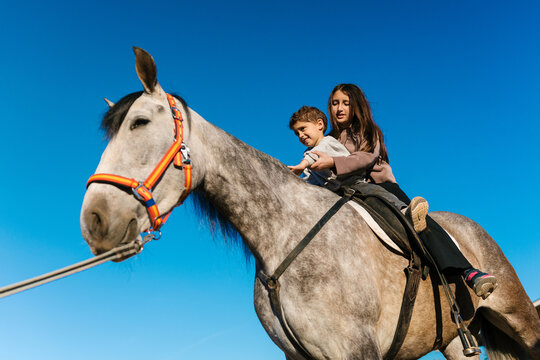 Children riding horse together against blue sky