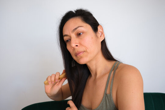 Woman Brushing Long Hair in a Simple Room During the Day