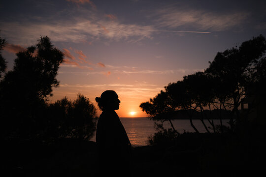A person standing at sunset with the sea in the background