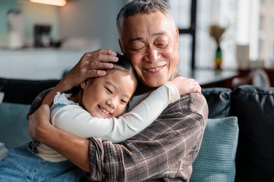 Grandfather and granddaughter share a loving embrace on the couch.