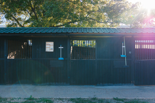 Empty horse stalls with cleaning tools at sunset
