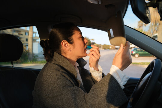 A woman gets ready in her car while it's parked before work