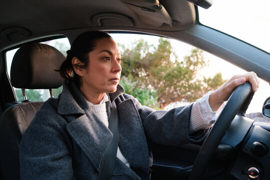 Woman Drives Car During Sunset in Suburban Area