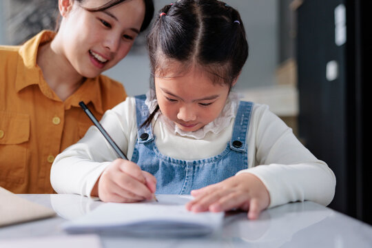 Girl writing with mother watching and smiling.