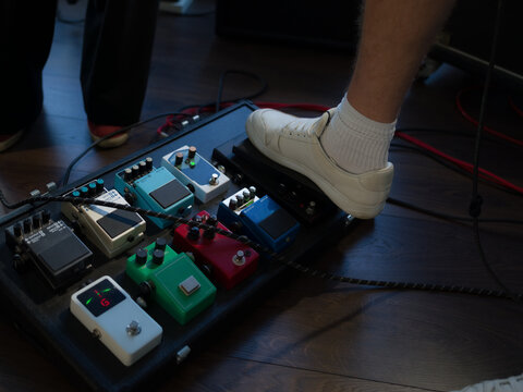 Guitarist using sound effect pedals while playing electric guitar 