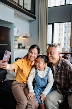 Three generations smile for a selfie in a modern home.