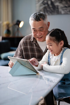 Grandfather and granddaughter using a digital tablet together