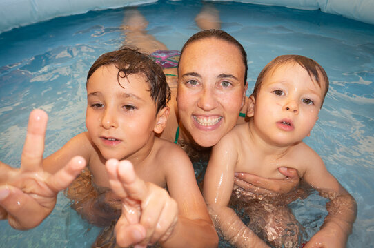 Mother and kids playing in inflatable pool at home