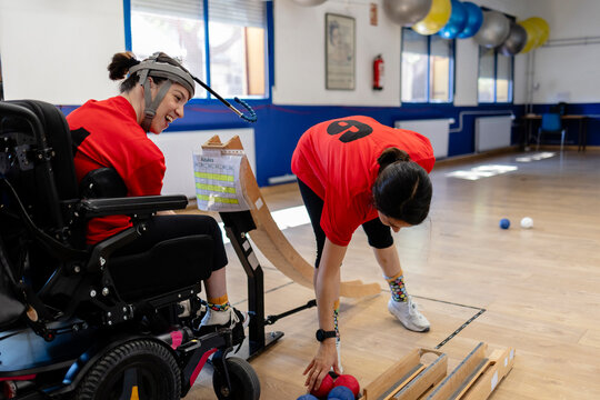 Disabled woman competing in boccia sport with assistant