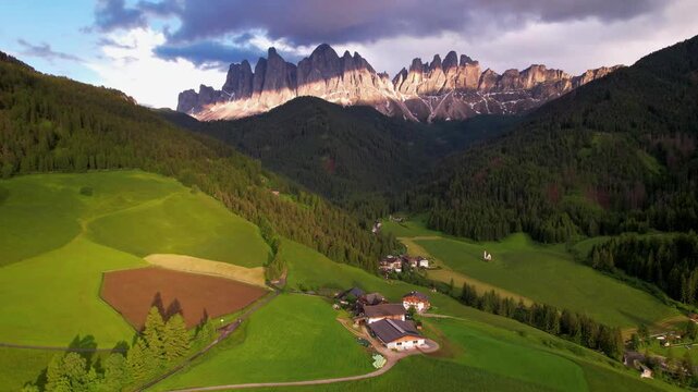 Cinematic Sunset Drone Reveal of Santa Maddalena Village and Iconic Alpine Chapel in Val di Funes Dolomites Italy Majestic Odle Peaks Green Fields Golden Hour Light Epic Mountain Scenery 4K