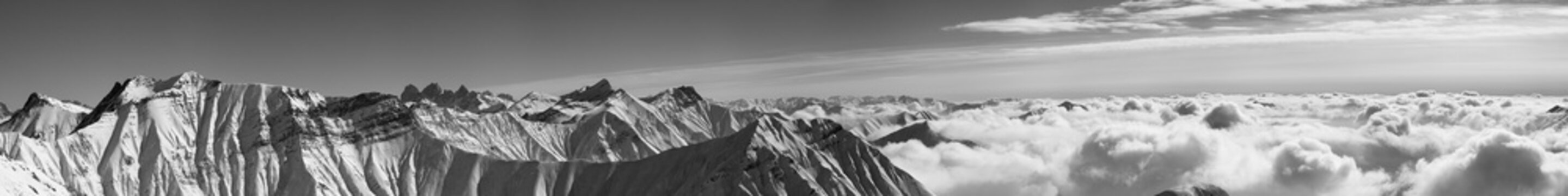 Panorama of snowy mountains covered with clouds at winter