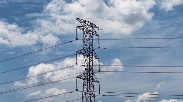 A tall electrical transmission tower supporting multiple high voltage power lines stretches across a partly cloudy sky, showcasing infrastructure essential for energy distribution.