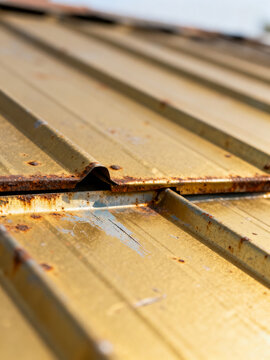 Close-up of a rusty, corrugated metal roof with visible corrosion and weathering effects.