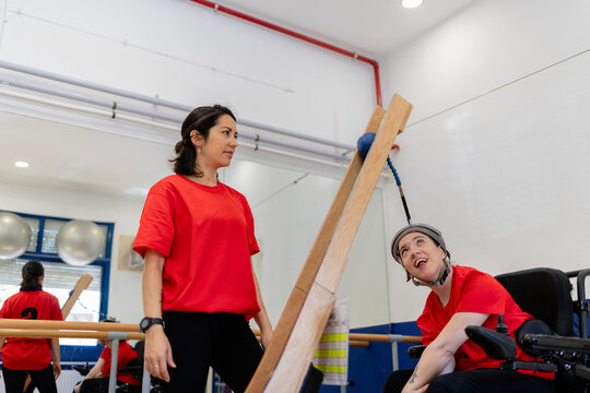 Woman in wheelchair playing adapted boccia game with therapist