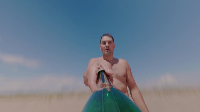 The guy throws and catches a bottle on the beach, developing dexterity and accuracy. A vacationing tourist has fun by tossing a plastic bottle in a few turns.